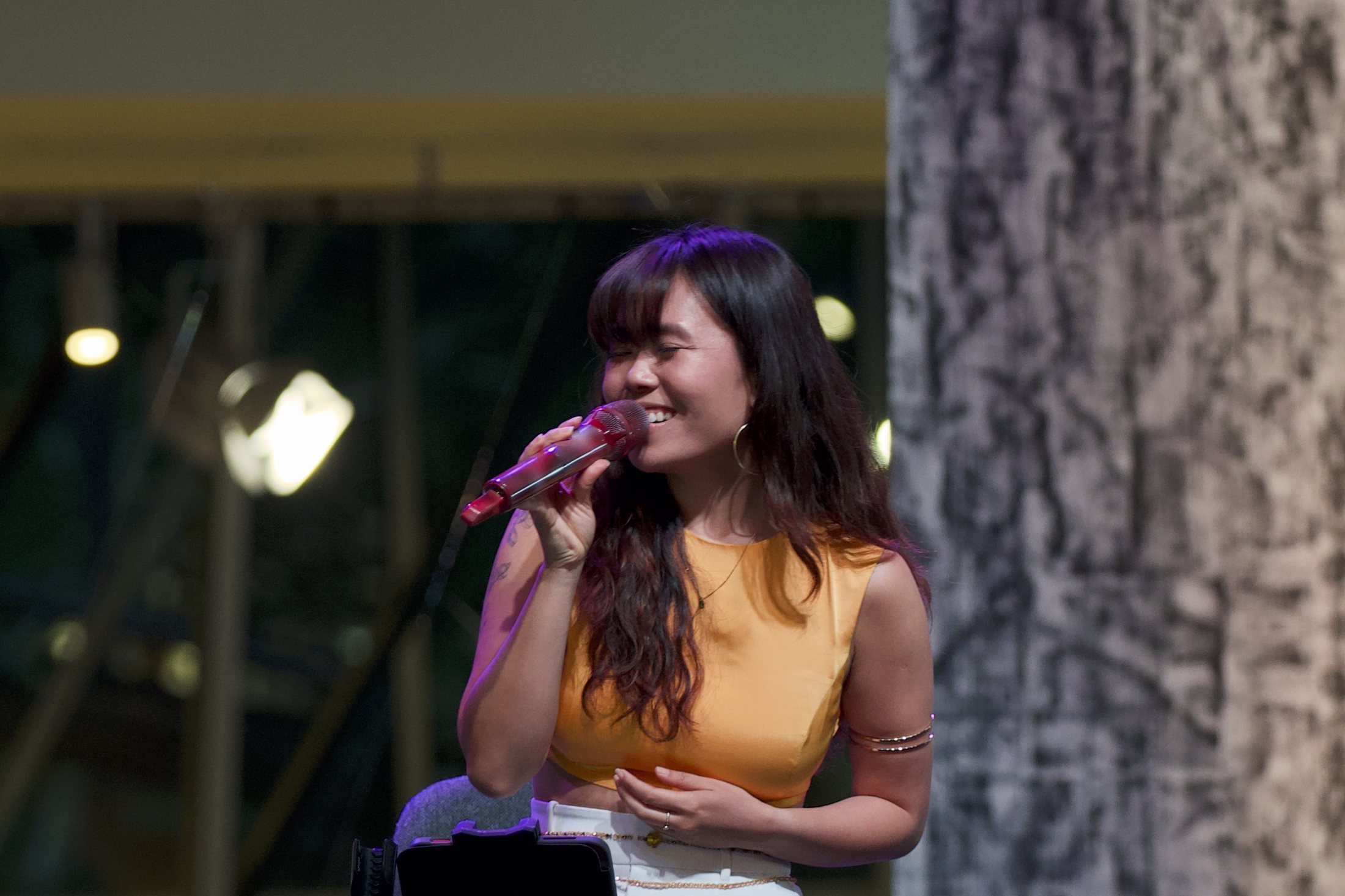elysrei singing on stage in an orange top